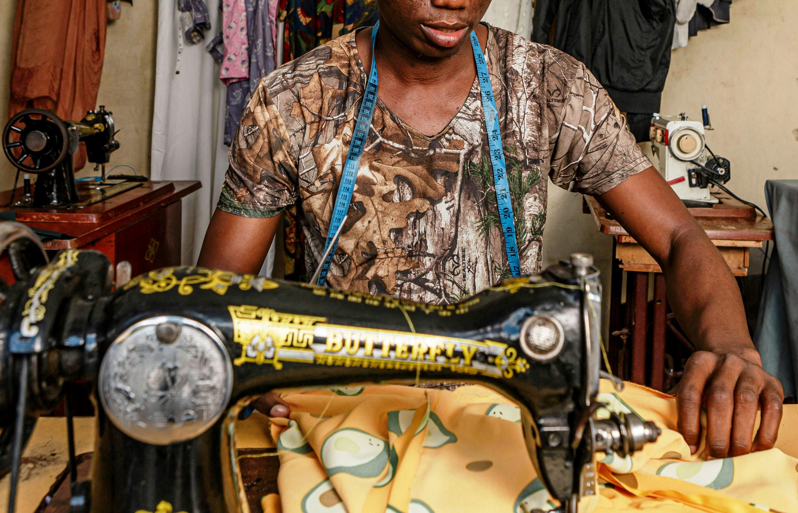 Afrikanischer Schneider fertigt ein Kleidungsstück aus traditionellem Stoff in einer Werkstatt an